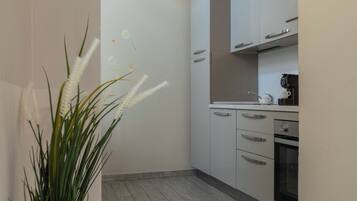 A kitchen with white cabinets, a coffee maker, and a potted plant with white flowers.