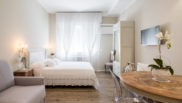 A bedroom with a bed, a chair, a wooden table, and a potted plant. - Maison Del Reno By Wonderful Italy (Bologna)