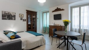 A room with a bed, a desk, a chair, a dining table, and a TV on the wall. - Rosso E Blu Di San Salvario By Wonderful Italy (Turin)
