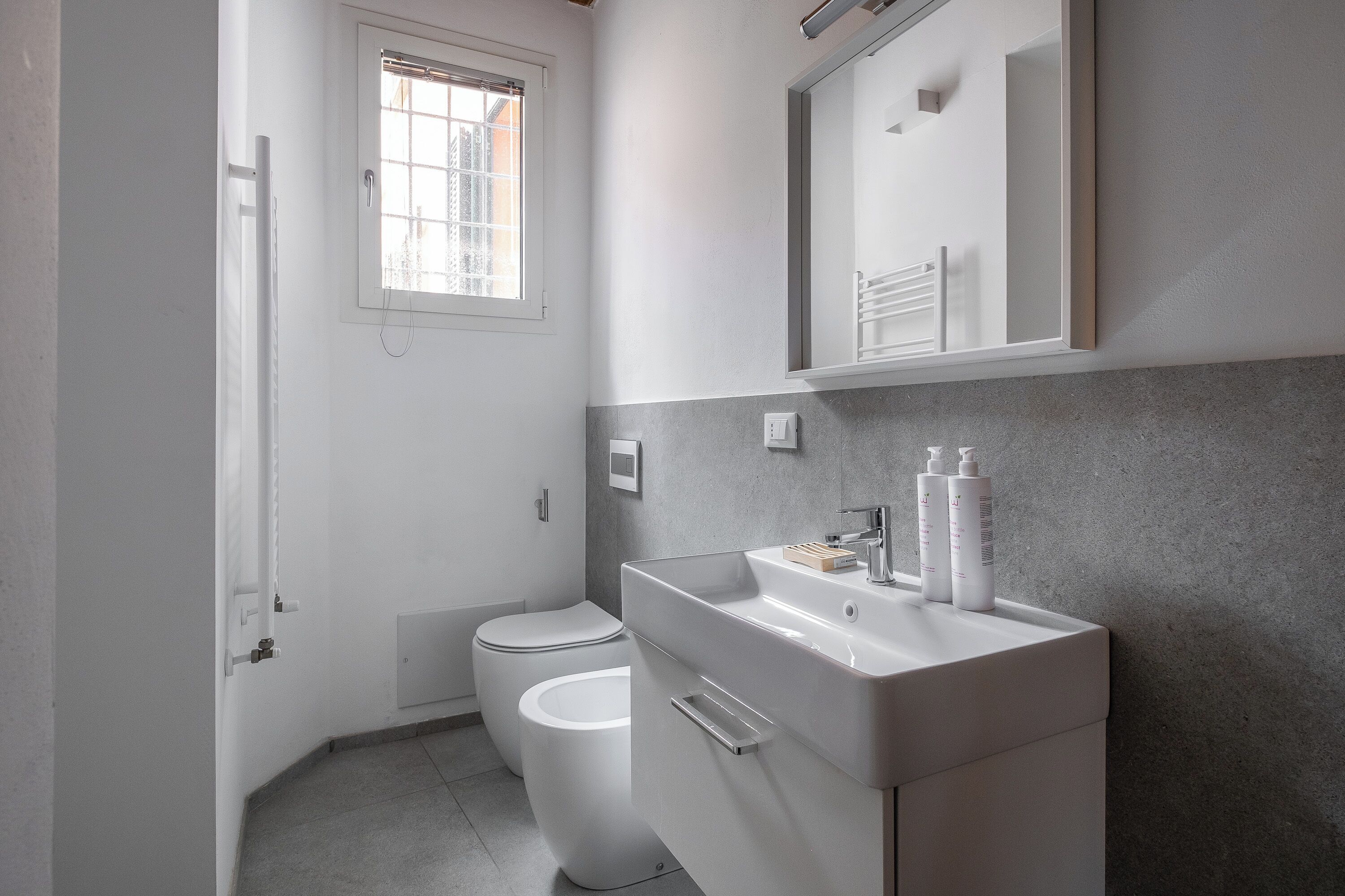 A modern bathroom with a toilet, sink, and window.