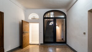 A hallway with a wooden door, a glass door leading to a staircase, and a speckled floor.