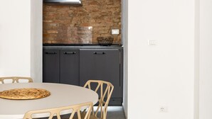 Una cocina moderna con pared de ladrillo, armarios oscuros y una mesa redonda con sillas.