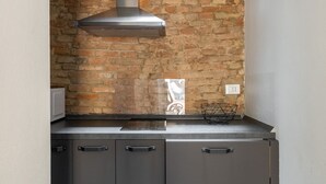 A kitchen with a brick wall, a stainless steel range hood, and a modern countertop.