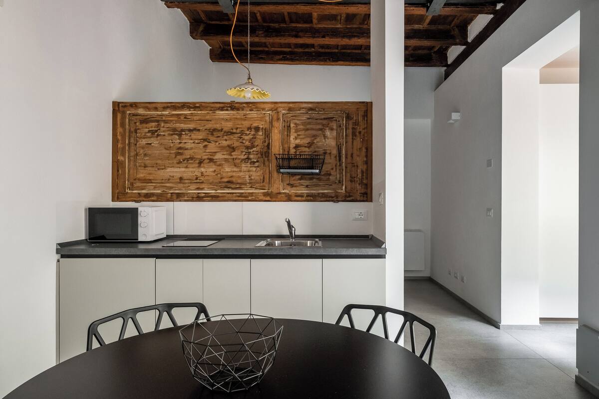 Una cocina moderna con un salpicadero de madera, una mesa de comedor negra con sillas y una lámpara colgante.