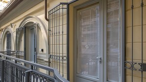 Fachada de edificio con balcón, una puerta grande con ventanal y un ventinilla con puerta.