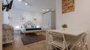 Une chambre moderne comprenant un lit, des tables de chevet, une armoire et un coin repas avec une table et des chaises.