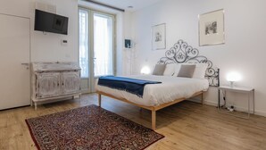 Un dormitorio con una cama, un armario, un televisor y una ventana.