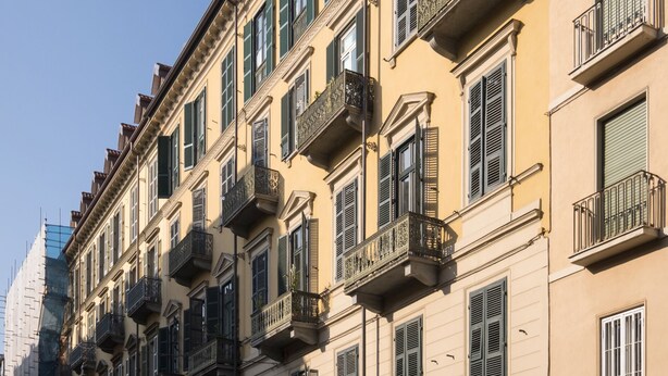 Una hilera de edificios de varios pisos con balcones y persianas.