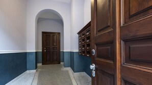 Un pasillo con una puerta doble, un buzón y suelo de mármol.