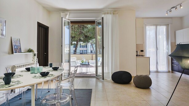 A modern kitchen with a dining area, a view of the outdoors, and a large window.