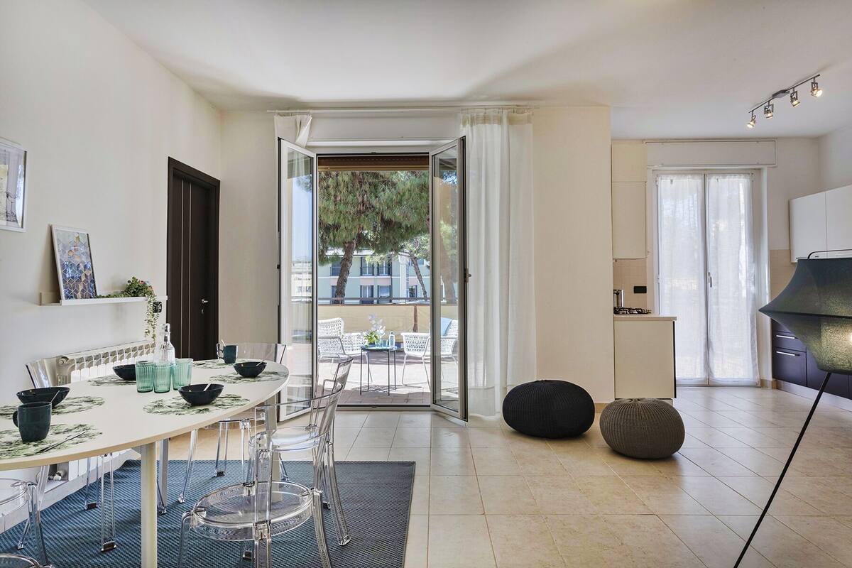 A modern kitchen with a dining area, a view of the outdoors, and a large window.