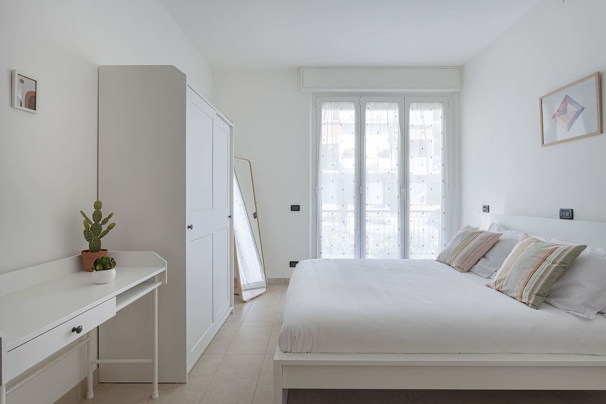 A minimalist bedroom with a bed, bedside table, and a potted plant.