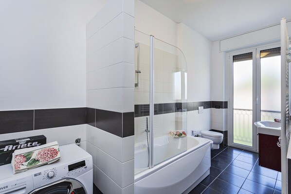 Un baño moderno con ducha de vidrio, inodoro integrado y lavadora.