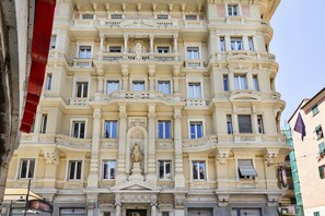 Un edificio de varios pisos con arquitectura clásica, que presenta balcones ornamentados y una estatua central.