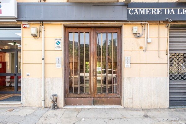 A building entrance with a wooden door, a sign reading "CAMERE DA LE", and a metal gate on the right. - Un Balcone Sull'Orto Botanico By Wonderful Italy (Palermo)
