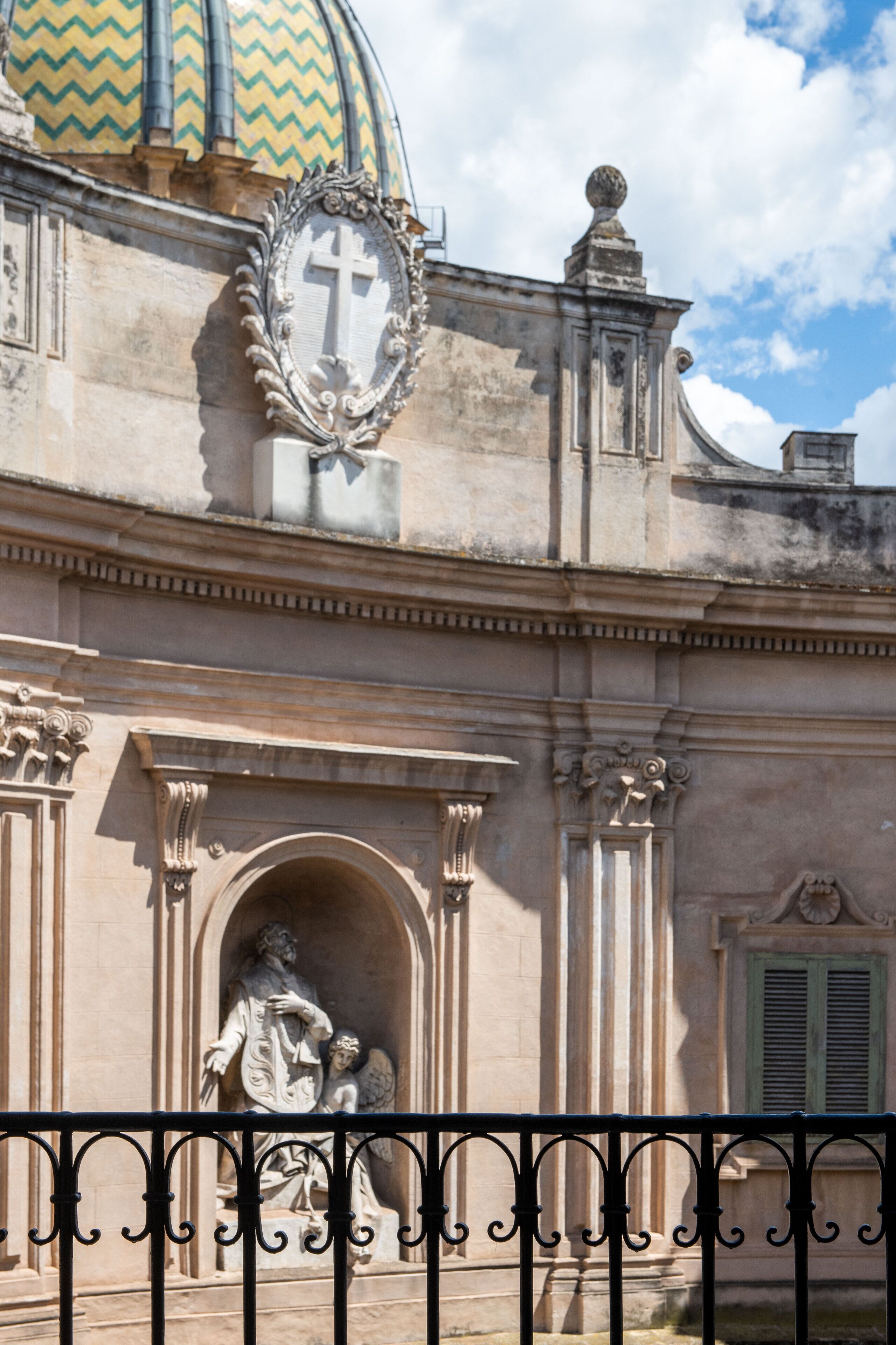 Edificio histórico con una cúpula, fachada ornamentada y una estatua de una figura sosteniendo a un niño.