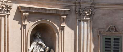 Edificio histórico con una cúpula, fachada ornamentada y una estatua de una figura sosteniendo a un niño.