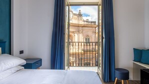 A hotel room with a balcony, a bed, a nightstand, a small table, and a chair. - Villena Plaza by Wonderful Italy (Palermo)