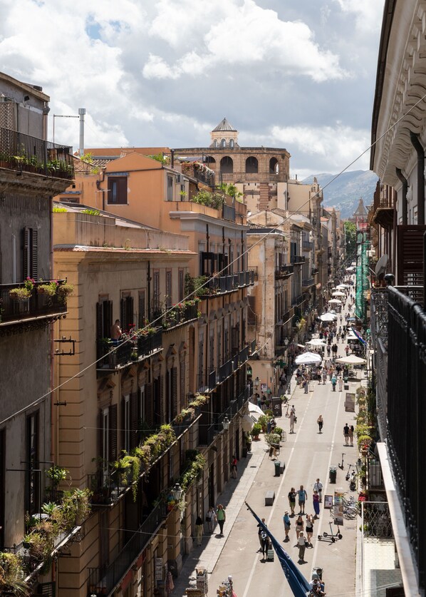 A bustling street with historic buildings, balconies with plants, and a clear sky. - Villena Plaza by Wonderful Italy (Palermo)