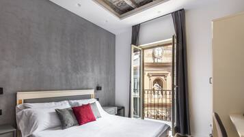 Una camera da letto moderna con un letto grande, una scrivania e un balcone con ringhiera in ferro battuto.