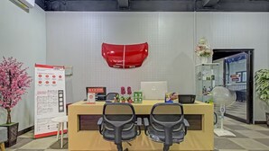 A reception desk with two office chairs, a red wall-mounted object, a whiteboard, and a potted plant. - Capital O 3198 Sukomanunggal Inn (Surabaya)