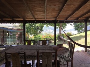An outdoor patio with a table set for dining, surrounded by chairs, and a hammock.