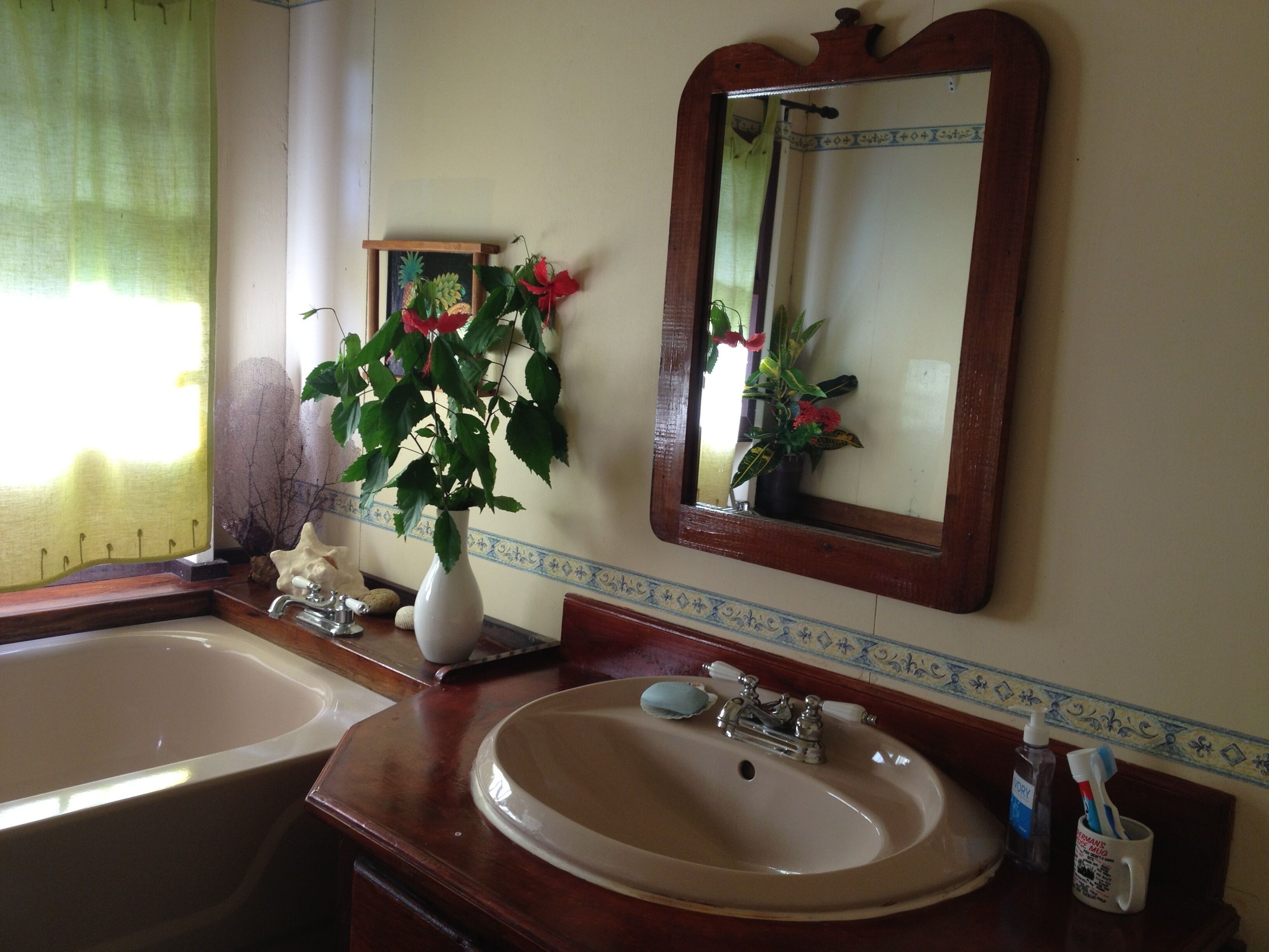 A bathroom with two sinks, a mirror, and a vase with flowers.