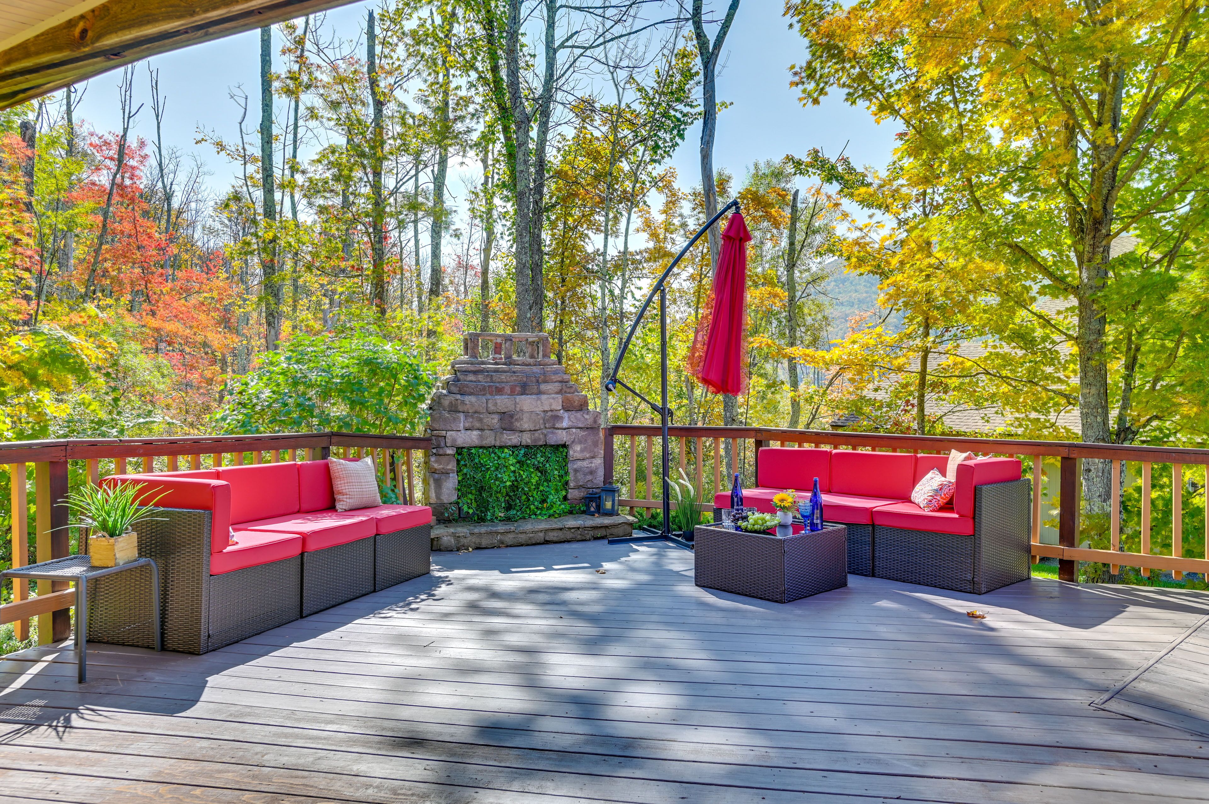 Une terrasse en bois avec des sièges d’extérieur rouges et une cheminée en pierre.