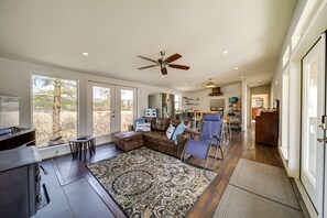 A spacious living area with a large sectional sofa, a ceiling fan, and a view of the outdoors. - Lake-View 4-Season Retreat in Republic! (Republic)