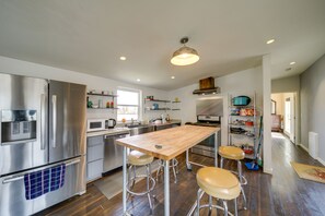 A modern kitchen with stainless steel appliances, a wooden dining table, and bar stools. - Lake-View 4-Season Retreat in Republic! (Republic)
