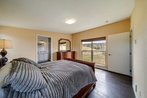 A bedroom with a large bed, a dresser, a mirror, and a door leading to a balcony. - Lake-View 4-Season Retreat in Republic! (Republic)