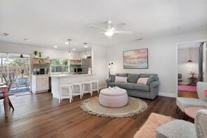 Relax in this stylish living space with a large sofa, round ottoman, and modern kitchen area.