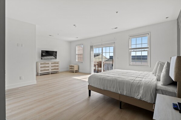 Ein modernes Schlafzimmer mit einem großen Bett, einem Fernseher und einem Balkon.