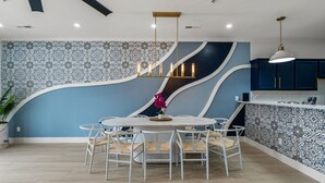 Une cuisine moderne avec une table à manger ronde, des chaises blanches et un luminaire central.