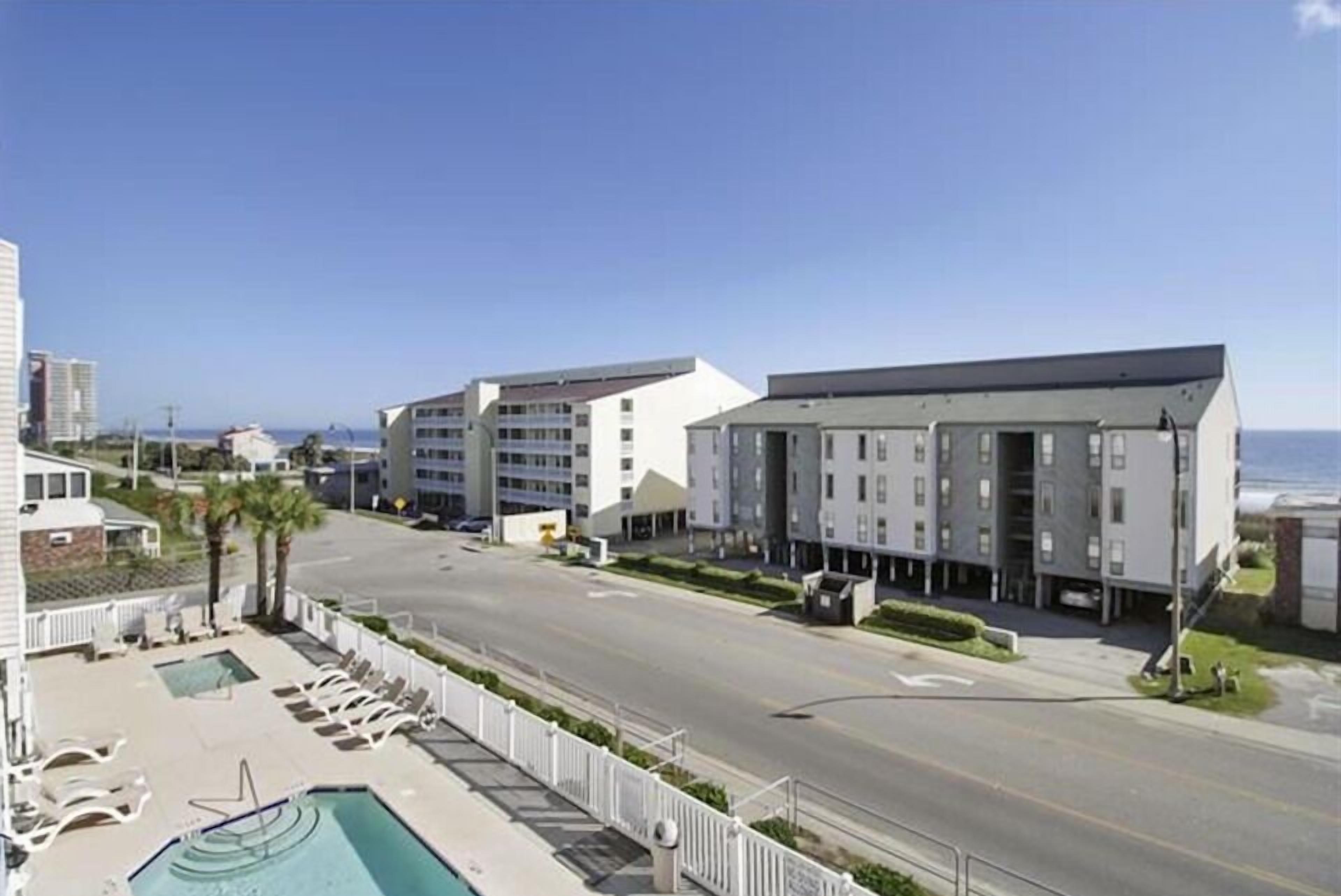Ein modernes Hotel mit Schwimmbad, Straßenansicht und blauem Himmel.
