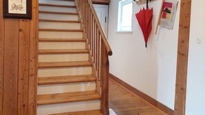 Una escalera de madera con barandilla, que lleva a una habitación con una puerta blanca y una ventana.
