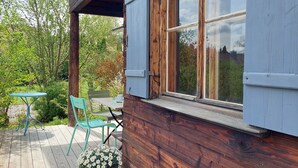 Una cabaña de madera con terraza, una mesa, sillas y una planta en maceta.