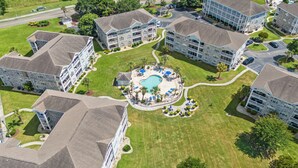 A residential complex with multiple two-story buildings, a central swimming pool, and well-maintained lawns. - Quiet Myrtlewood Condo for 4 • Family Fun & Golf Nearby (Myrtle Beach)