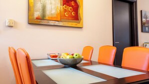 A dining area with a table, chairs, a fruit bowl, and a painting on the wall. - Seaside Luxury Residence near the Airport (Nea Makri)
