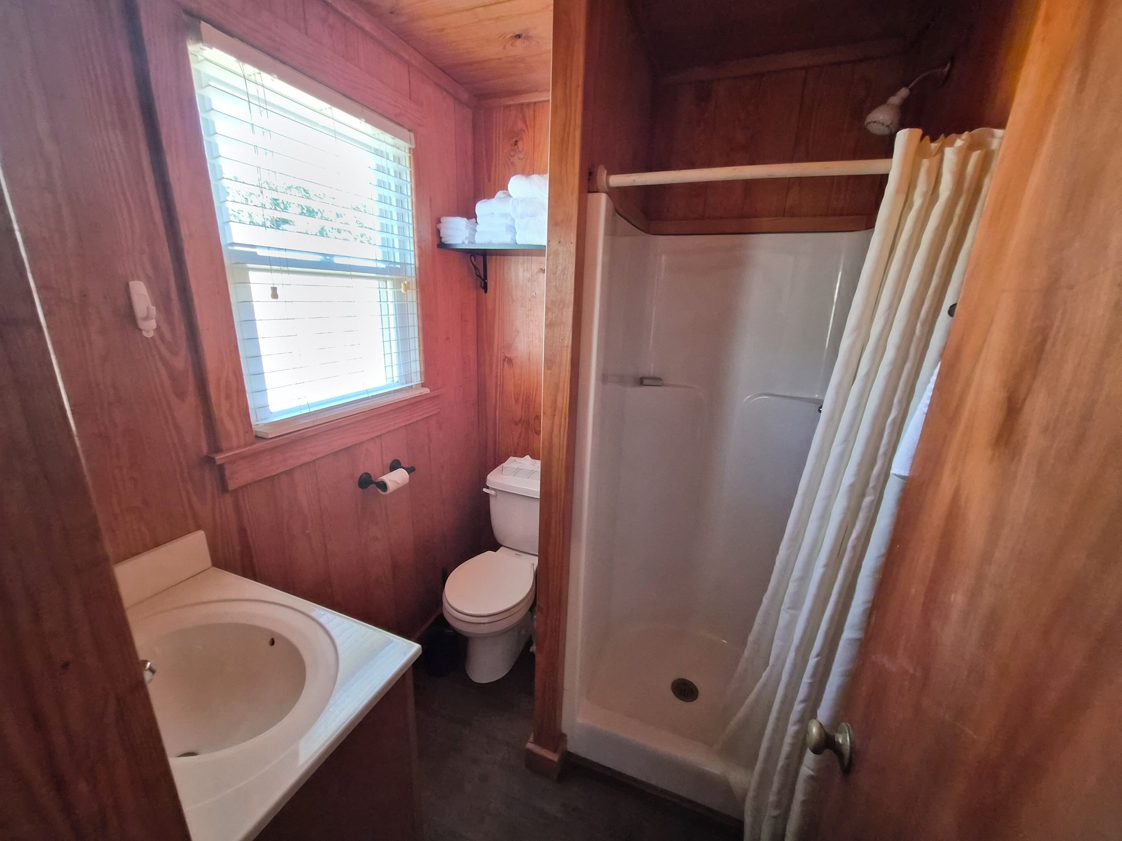 A wooden bathroom with a bathtub, toilet, and shower.