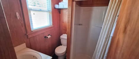 A wooden bathroom with a bathtub, toilet, and shower.