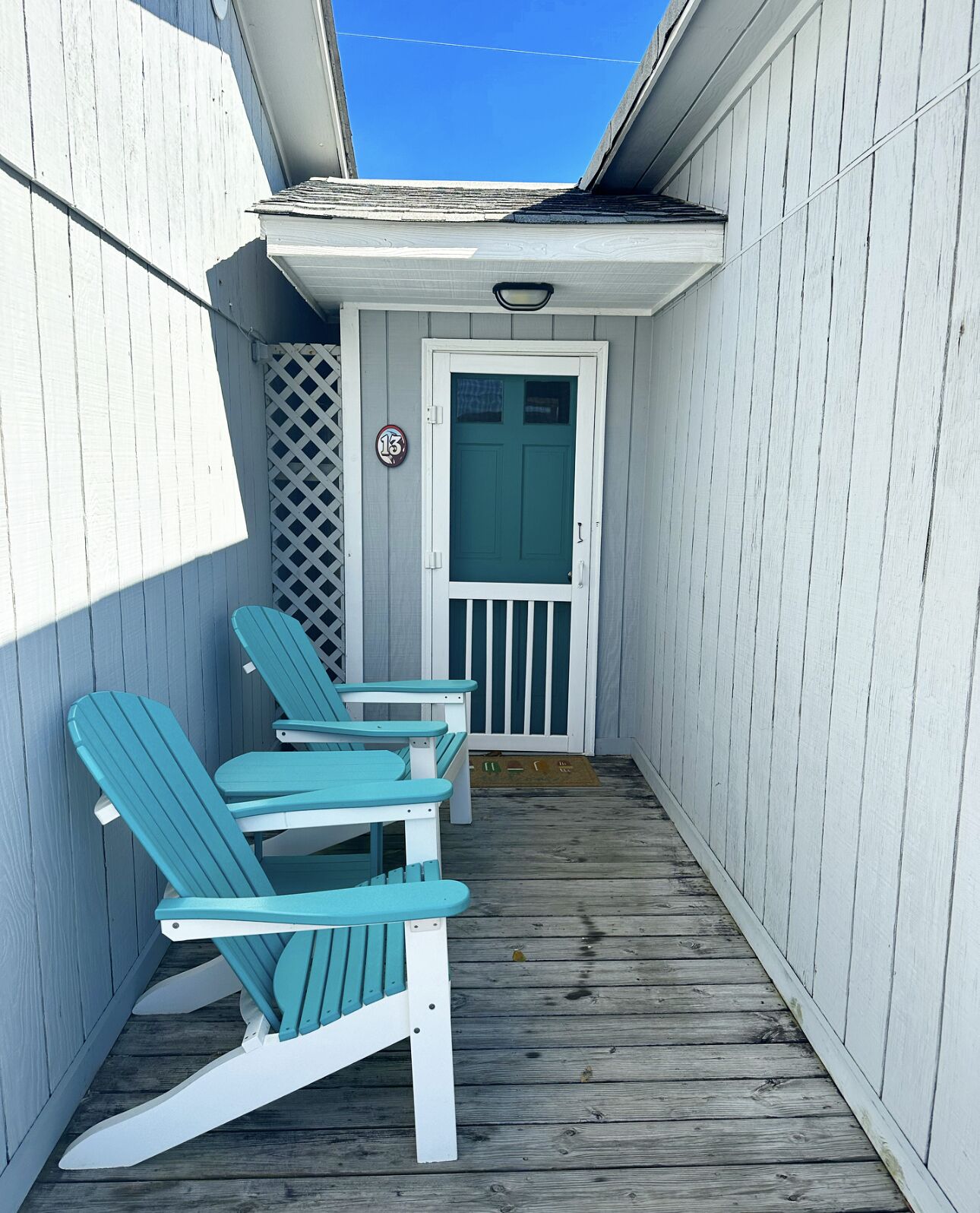 A narrow wooden deck with a white door and a small porch area.