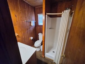 A wooden-paneled bathroom with a toilet, sink, and shower. - SandSpur Ocean Cottages (Nags Head)