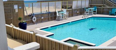 A swimming pool with a wooden deck, chairs, and a lifeguard stand.