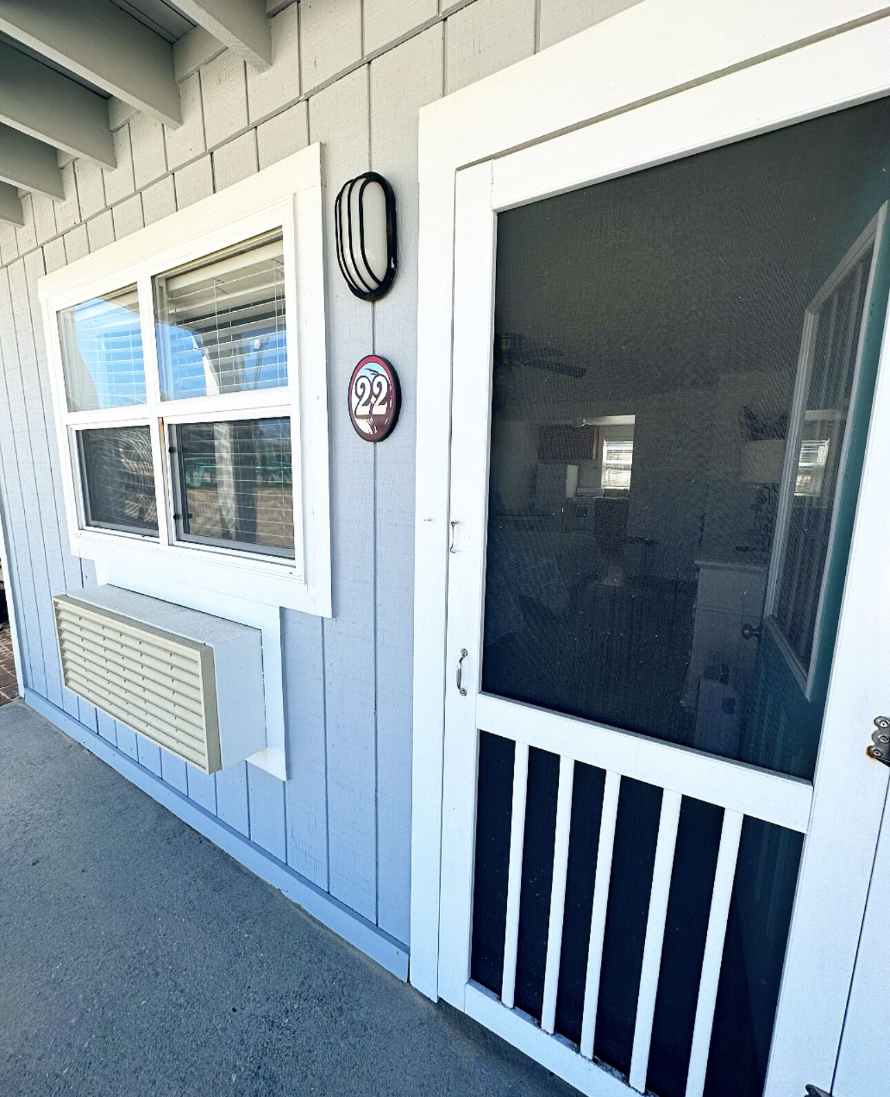 A house with a white door, a window with a screen, and a mailbox with the number 22.