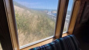 A room with large windows, a striped cushion, and a wooden wall.
