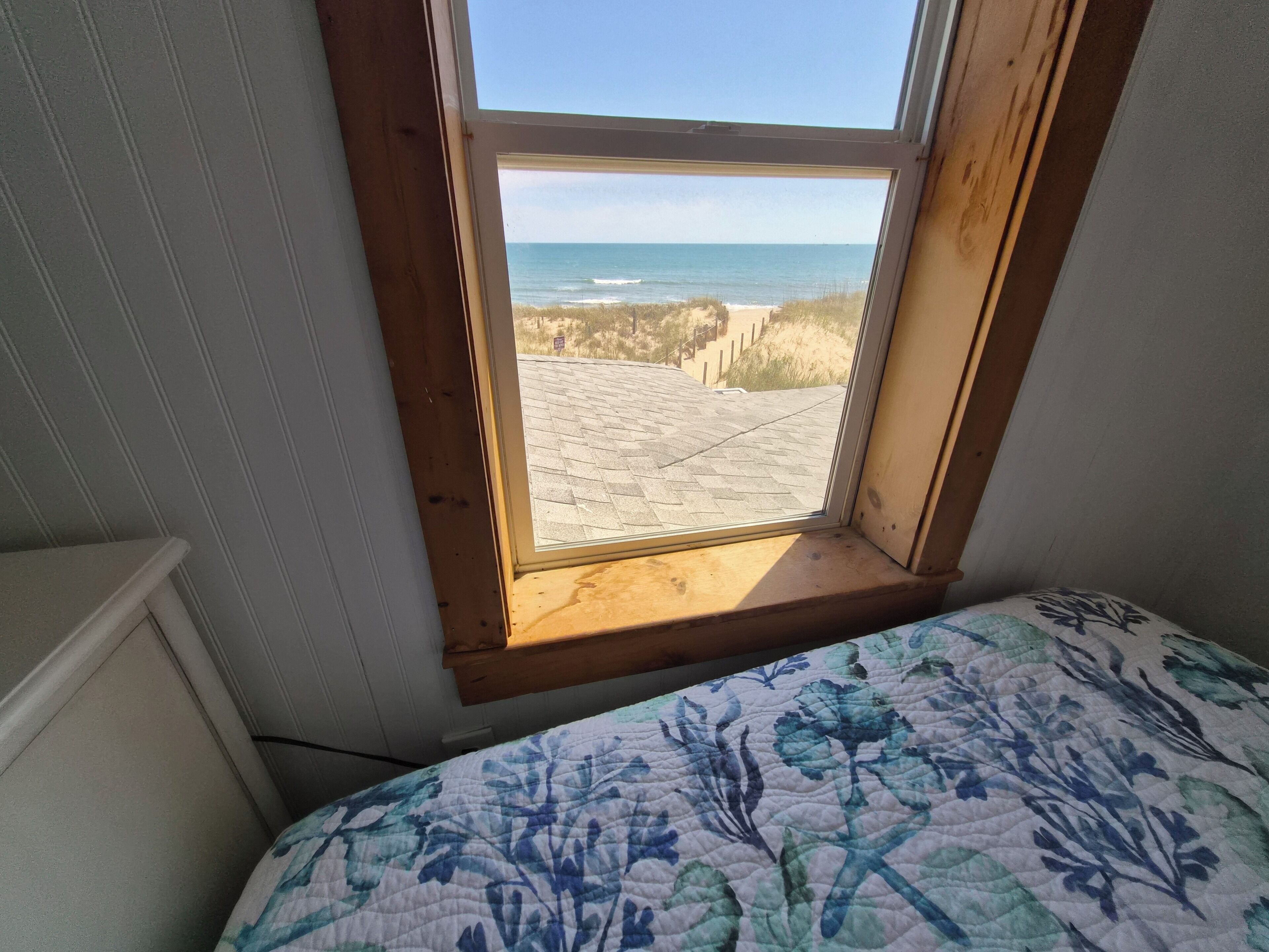 A bedroom with a window overlooking a beach.