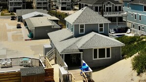 A beachfront property with a wooden deck, a small building with a balcony, and a sandy beach.