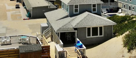 A beachfront property with a wooden deck, a small building with a balcony, and a sandy beach.