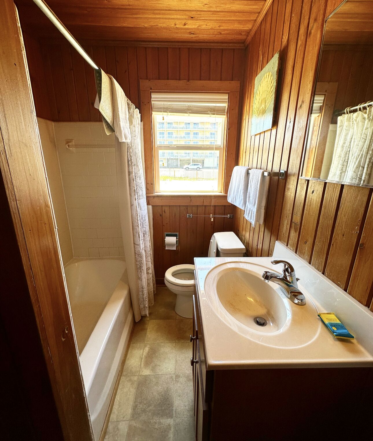 A compact wooden bathroom with a bathtub, toilet, and sink.